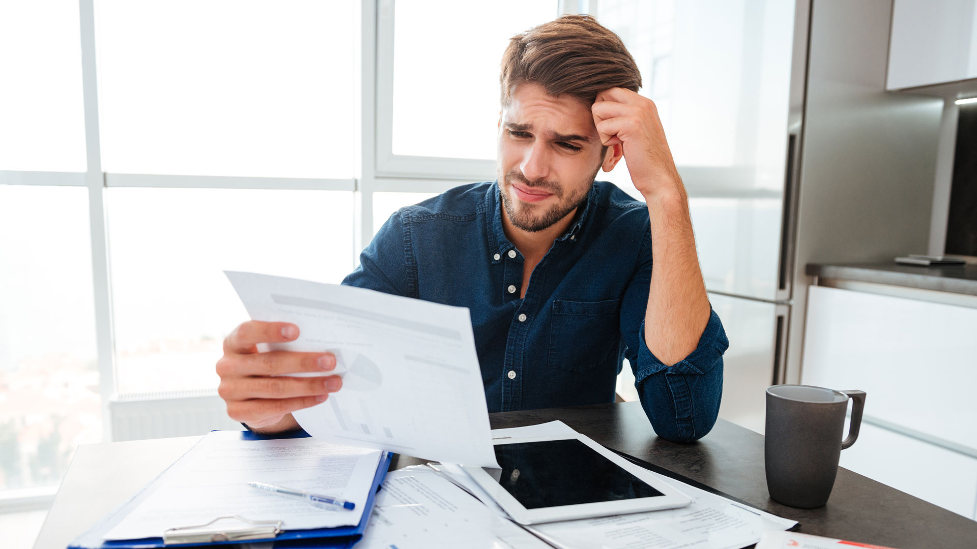 Confused man is looking at the document with stats