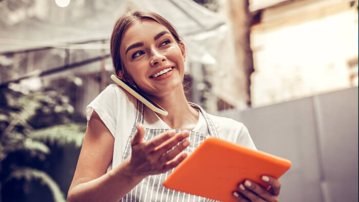Positive happy woman having a phone conversation and holding a tablet device.