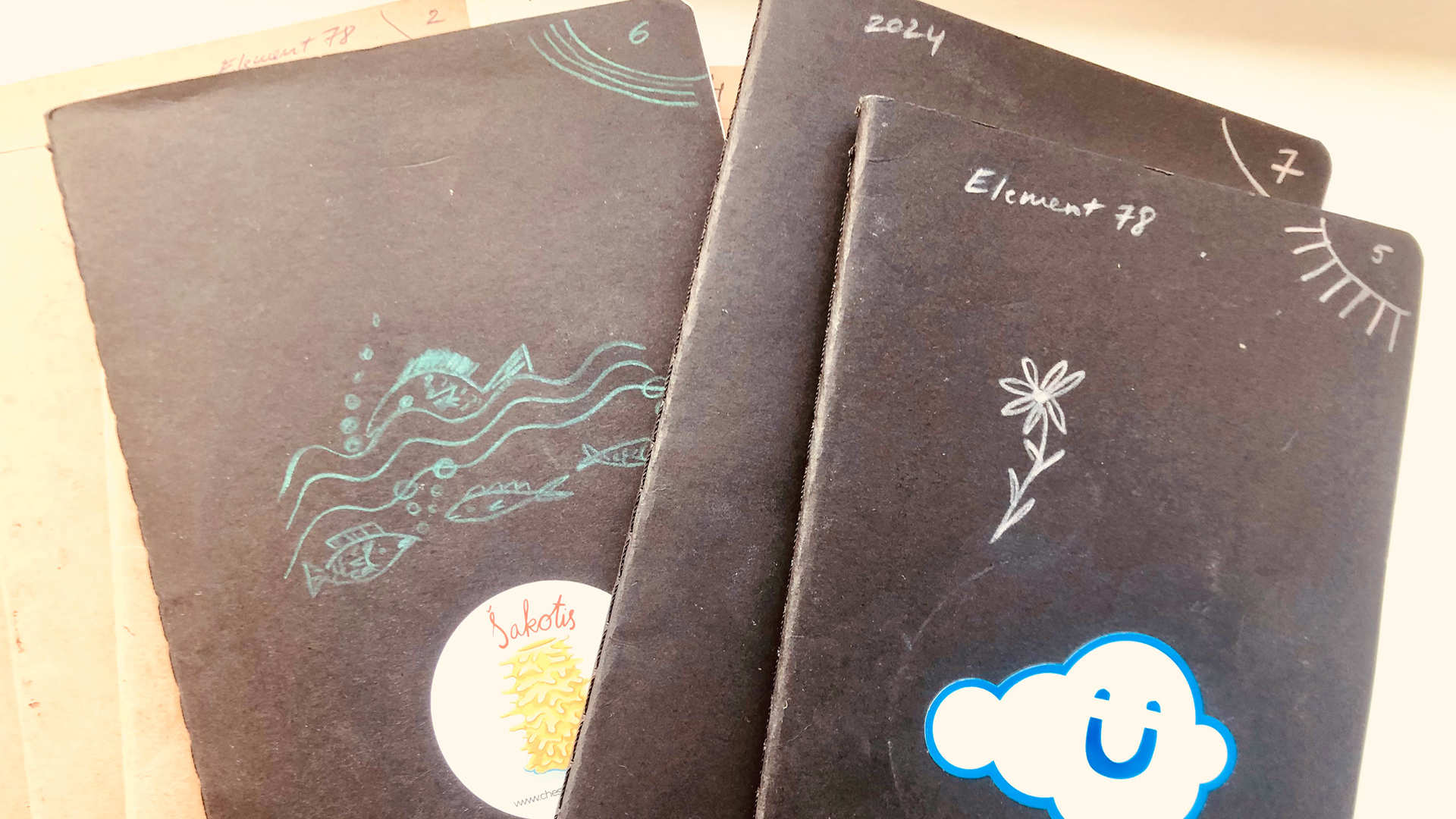 A group of black notebooks with stickers on the front.