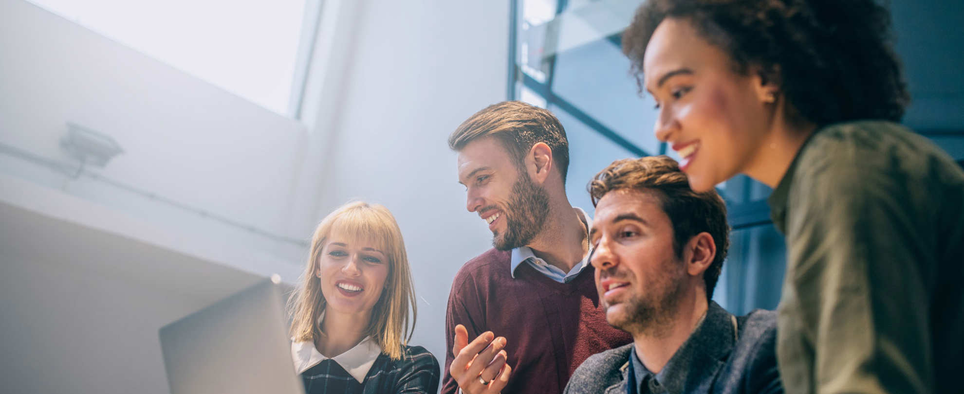 A group of people are looking at the laptop on the table.