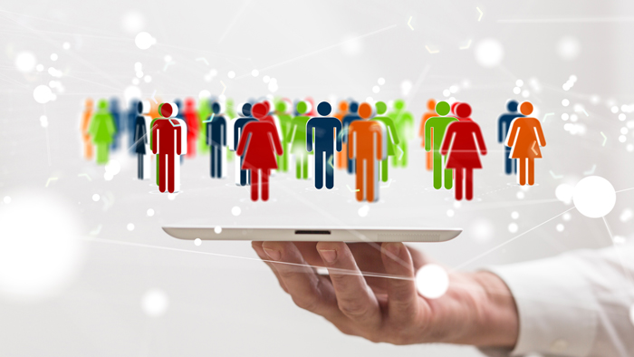 A hand holding tablet device with colourful people figures floating above, representing inclusion and diversity.