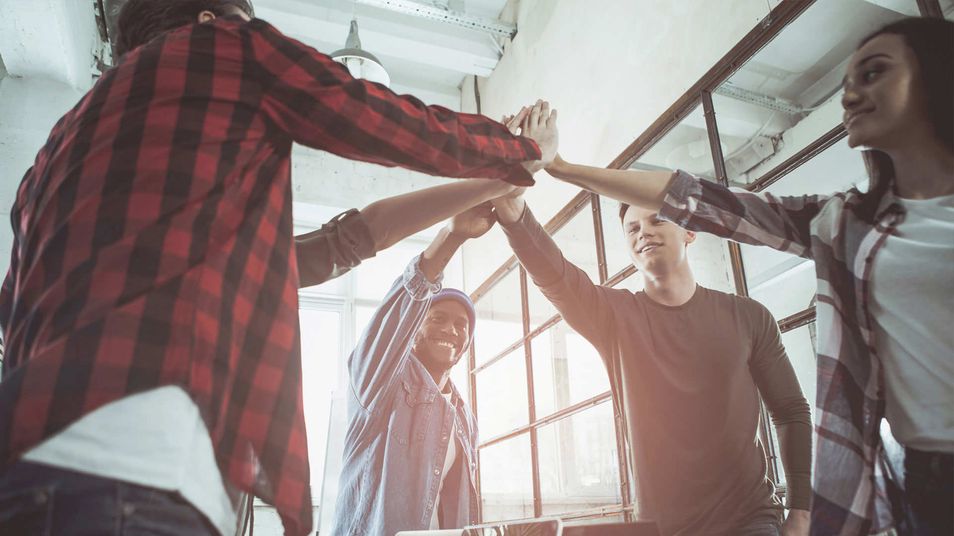 people in the office touching hands together and smiling