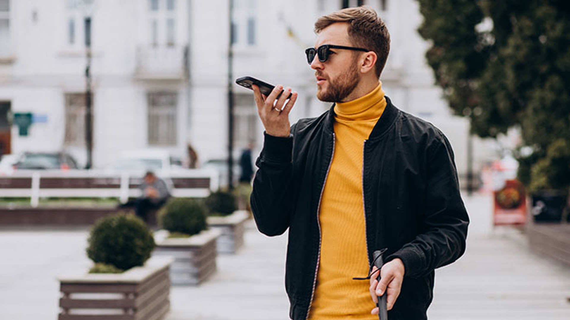 Young blinded man using phone and sending voice message