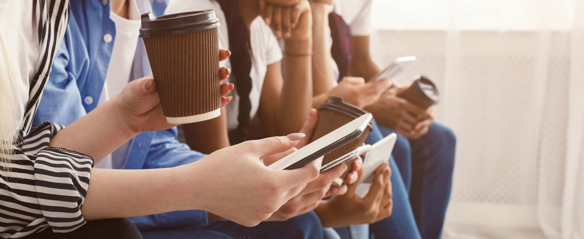 Teenagers group sitting in a row and holding phones