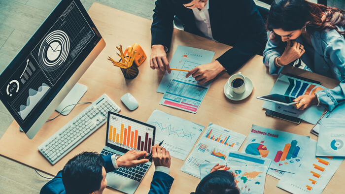 Business people sitting around the desk and looking at the statistics data.